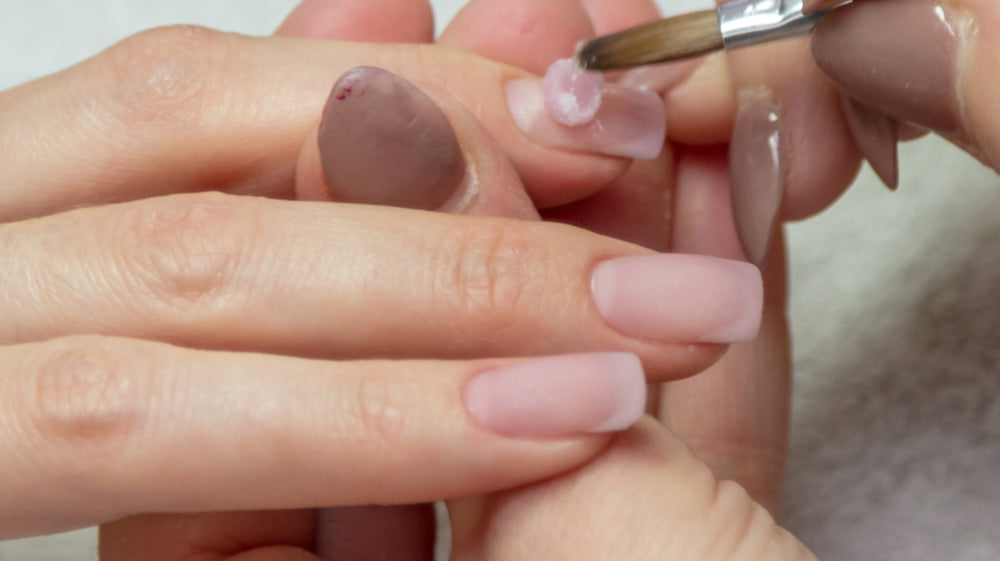 Applying a bead of clear acrylic to the nail