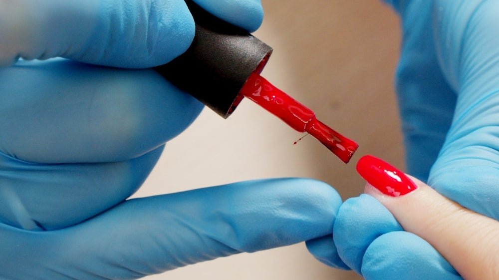 Nail tech painting red gel polish