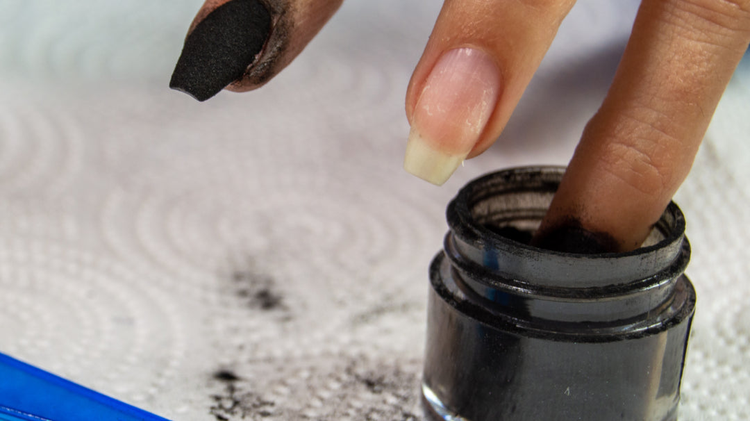 Woman dipping her nails into black dip powder