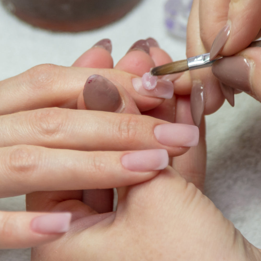 Applying a bead of clear acrylic to the nail