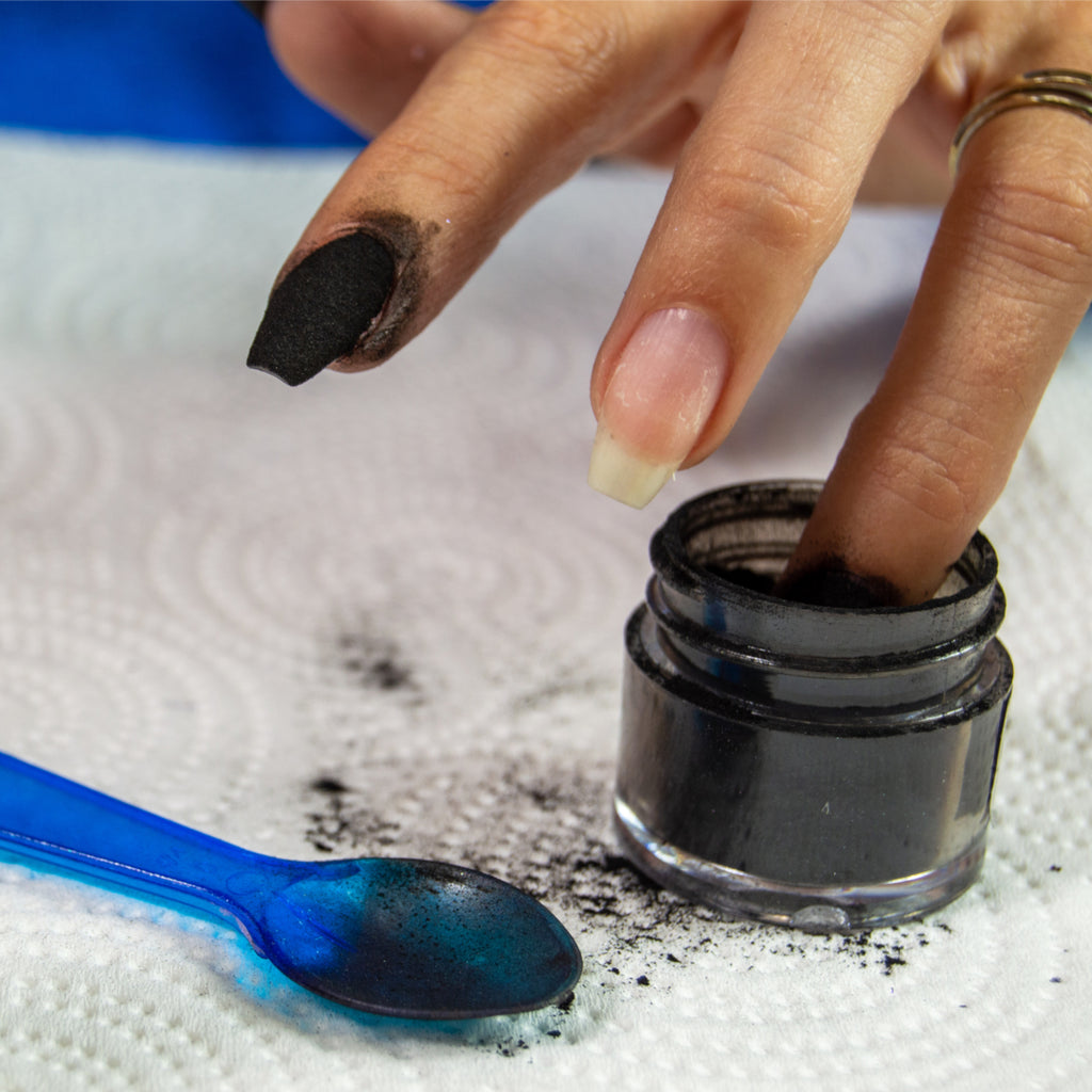 Woman dipping her nails into black dip powder